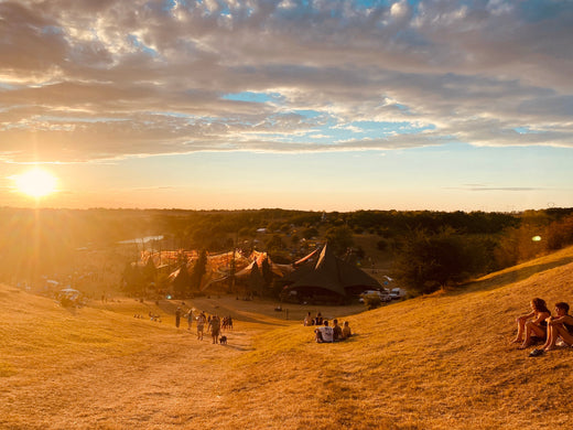 Imagem registrada por nós no Ozora festival 2022, onde mostra um vale com a pista principal e um lindo por-do-sol ao fundo.